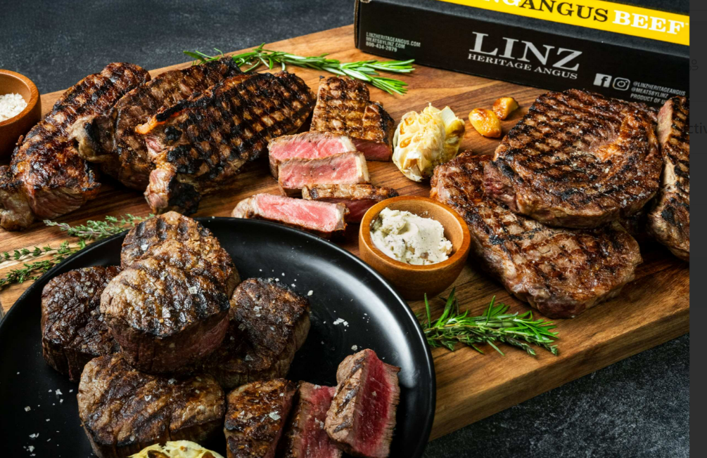 11 Incredible Compound Butter Recipes for Steak Several cooked steaks sit on a wooden cutting board. Small bowls of compound butter and herbs are on the board.