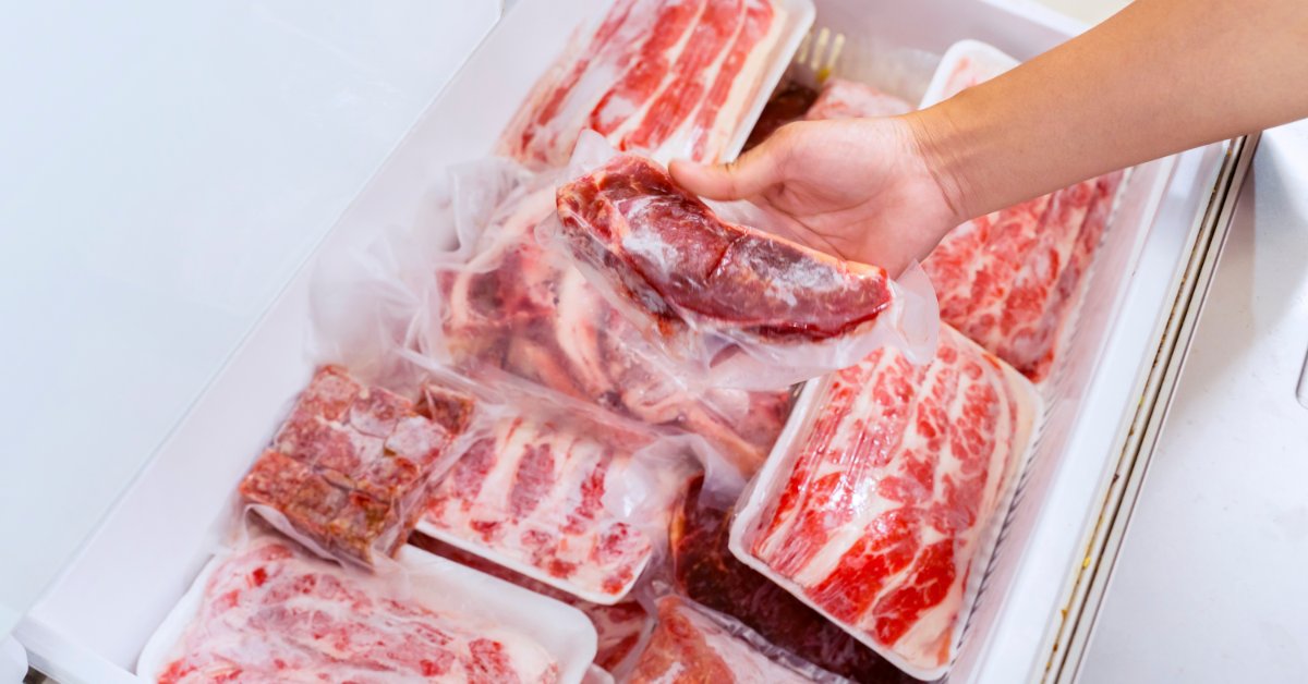 How Proper Meat Storage Helps Ensure Freshness and Taste A hand reaches into a chest freezer stocked with multiple plastic-wrapped packages of frozen raw meat and beef cuts.